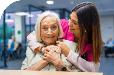 smiling young female caregiver assisting elderly woman with personal care